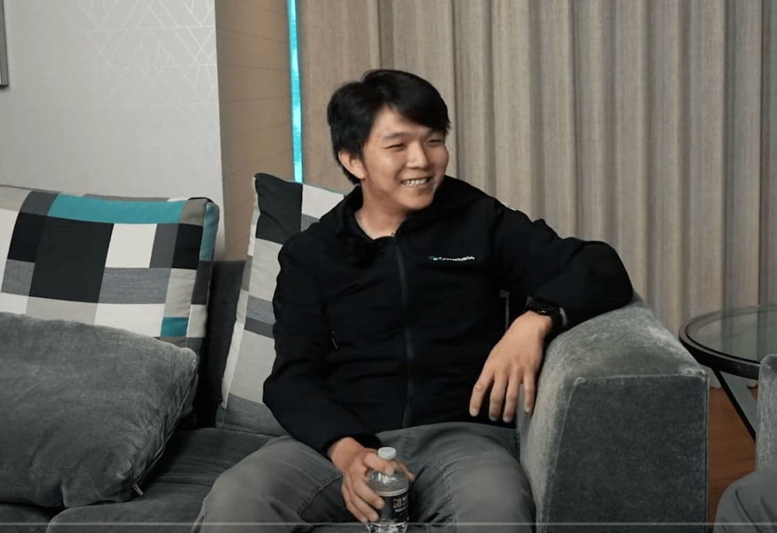 Clarence Chio, Co-Founder and CEO of Coverbase, sitting on a gray couch during a podcast interview