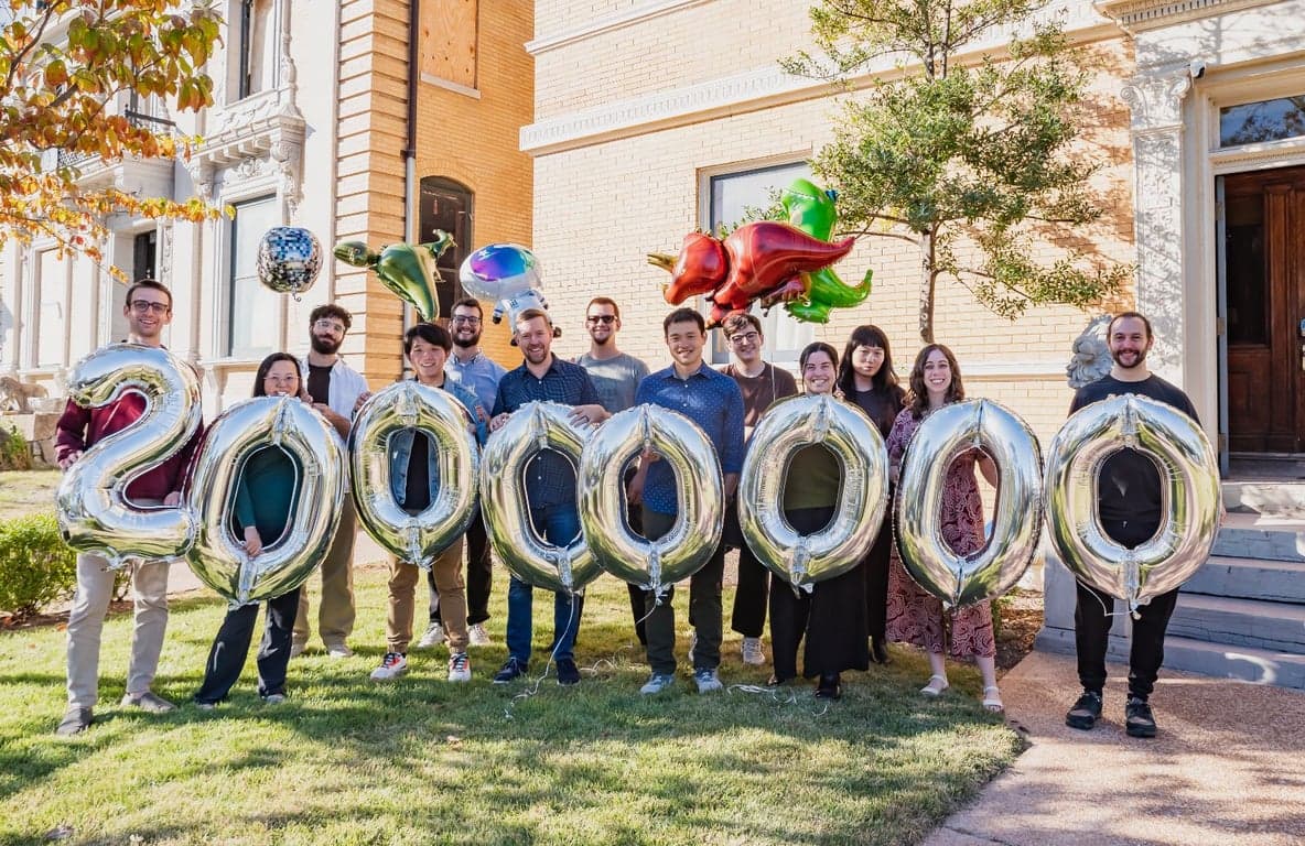 Coverbase team celebrating $20M funding milestone with large silver number balloons spelling 20000000